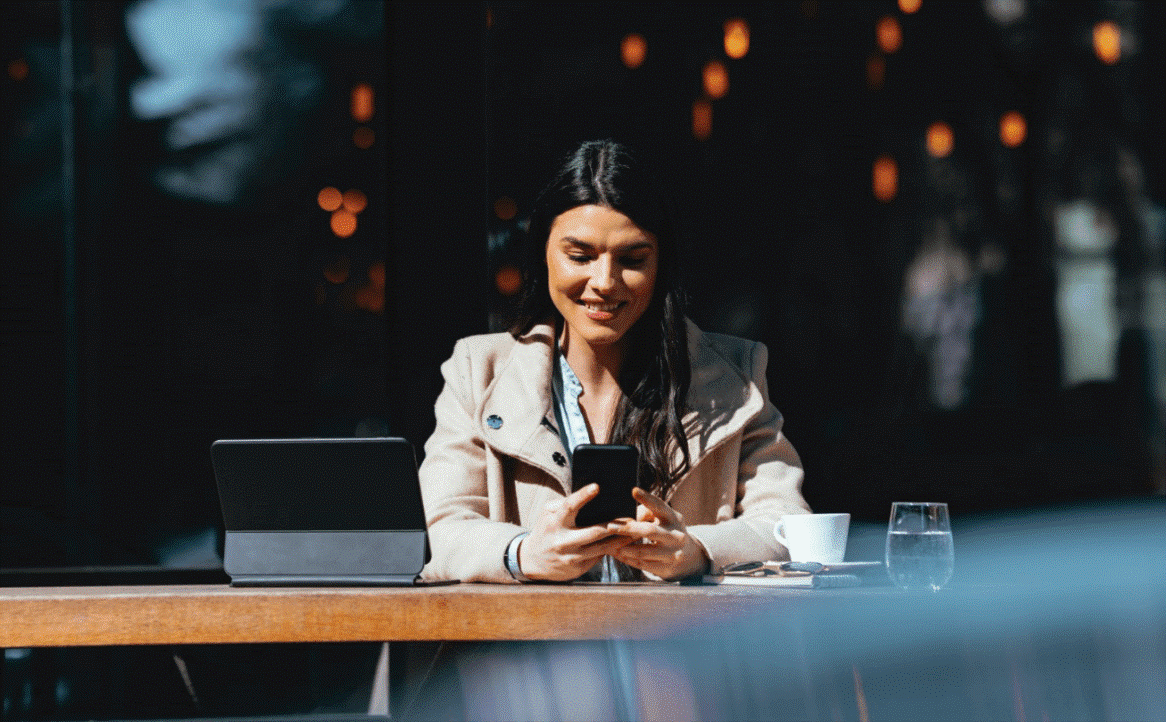 A lady sitting outside a coffee shop on her mobile phone