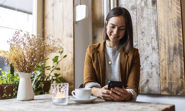 Lady in a coffee shop holding her phone
