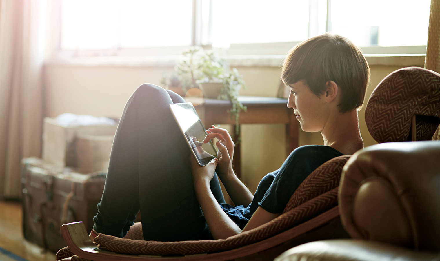 A lady sitting comfortably on a sofa with a tablet held on her knees