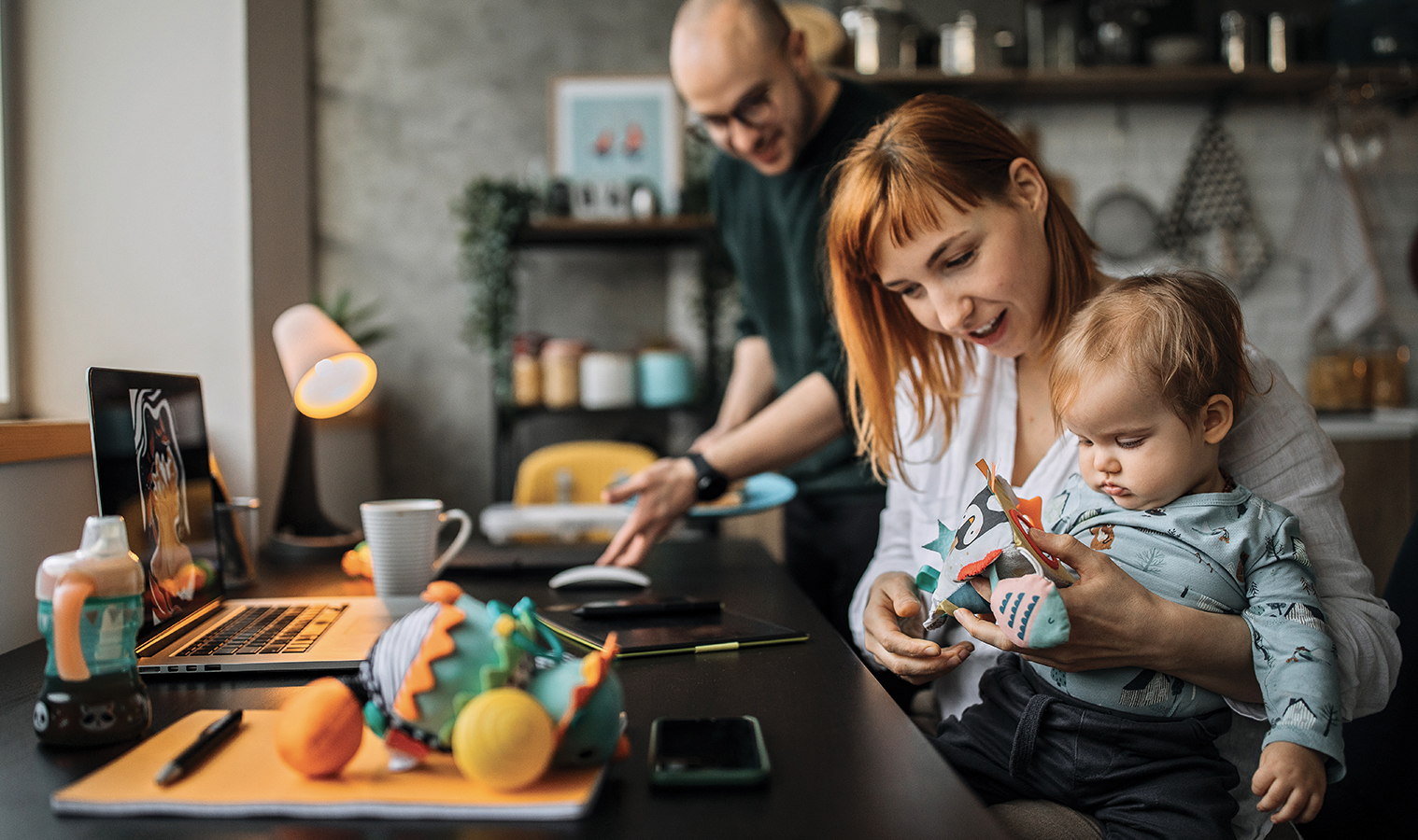 A family of three in a kitchen by the worktop preparing something to eat 